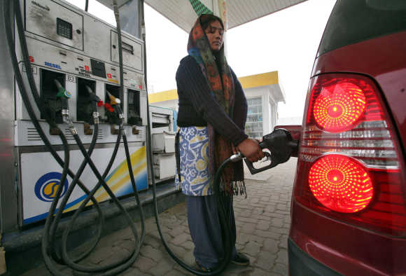 A woman fills a vehicle with petrol at a fuel station in Jammu.