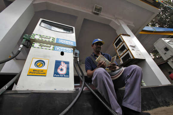 A worker counts cash at a fuel station in Mumbai.
