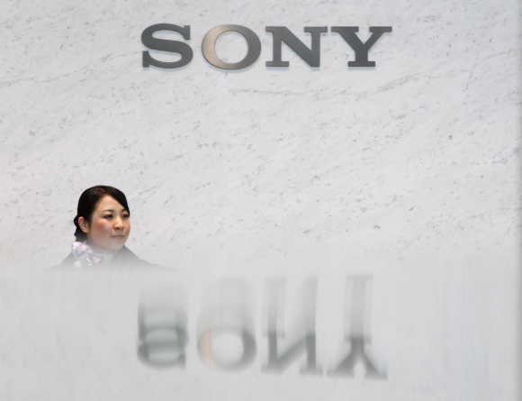 A receptionist of Sony Corp is pictured under the company's logo in Tokyo.