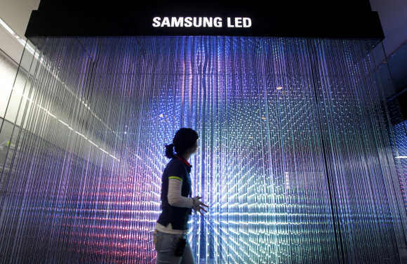 An employee of Samsung Electronics walks past LED lighting drums displayed for visitors at a showroom in Seoul.