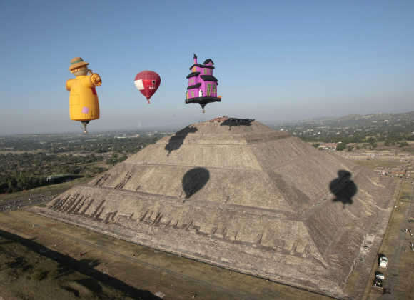 Hot air balloons float past people watching the sunrise at the Sun pyramids of Teotihuacan outside Mexico City.