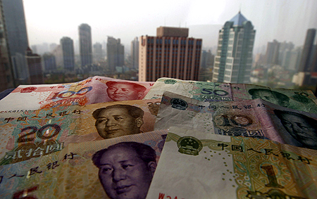 Different values of China's yuan banknotes are placed on a window sill as Shanghai's skyscrapers are seen in the background, in this photo illustration taken in Shanghai.