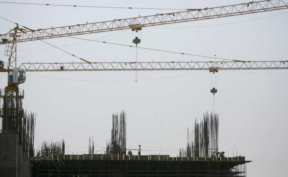 Workers stand on top of a building under construction in Mumbai.