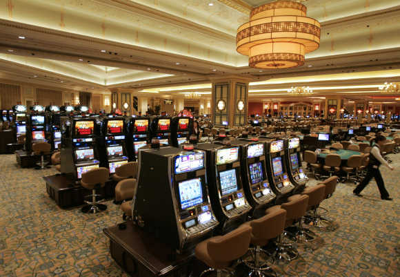 An employee walks past the slot machines in the casino at the Venetian in Macau.