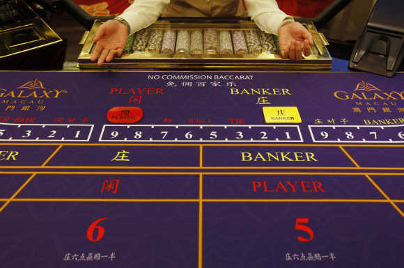 A croupier sits in front of a gaming table inside a casino on the opening day of Galaxy Macau.