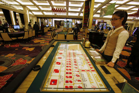 A croupier stands in front of a gaming table inside a casino on the opening day of Galaxy Macau.