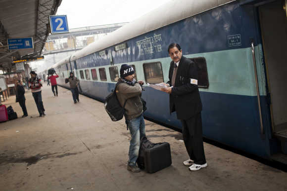 A passenger checks his seating on the Amritsar bound train, as he receives help from a conductor at the Nizamuddin Railway Station.