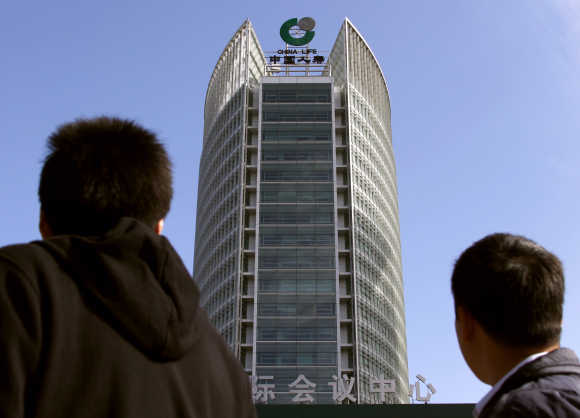 Pedestrians look up towards the headquarters of China's largest life insurance company, China Life, located in the financial district of Beijing.