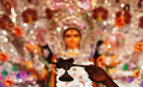 A priest holds a lamp while praying in front of an idol during Durga Puja in Kolkata.