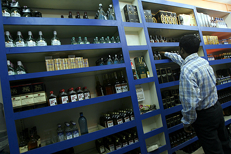 A man holds an alcohol bottle inside a wine shop.