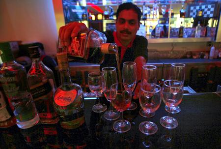 A bartender pours a glass of wine inside a bar.