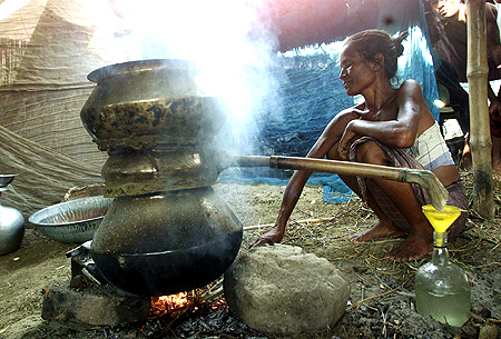 A Bodo tribal woman prepares rice wine inside a relief camp in Madnabori 70 kms (43 miles) north east of the city of Guwahati.