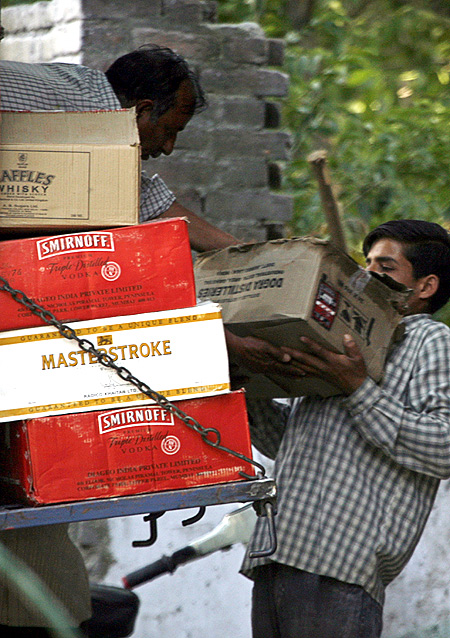 Labourers unload alcohol boxes from a truck outside a wine shop in Srinagar.