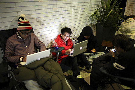 Gordan Cheng uses his iPhone and Mac computer while waiting in line overnight to purchase the new iPad at the Apple Store in Century City Westfield Shopping Mall in Los Angeles, California.