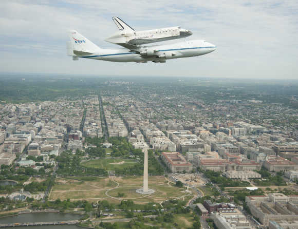 Space shuttle Discovery, mounted atop a Nasa 747 Shuttle Carrier Aircraft, flies over the Washington skyline.