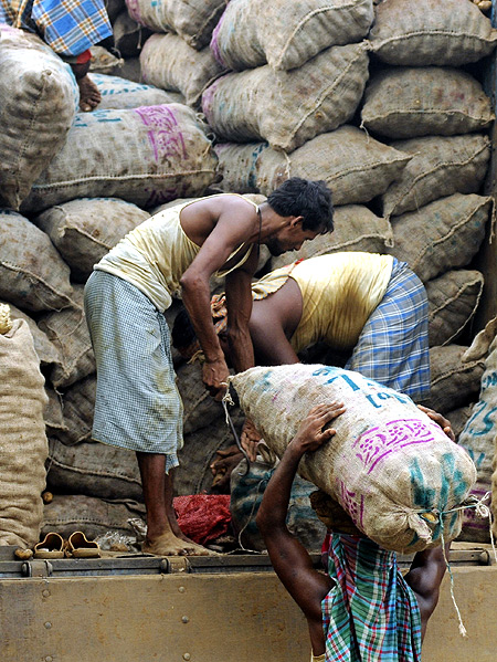 Labourers unload sacks of potatoes from a truck at a wholesale market in Agartala.