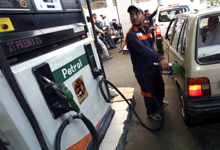 An employee fills a car with petrol at a gas station in Jammu.