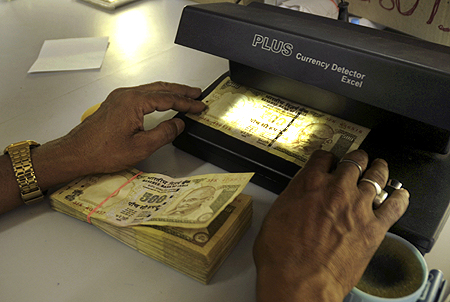 A cashier checks Indian currency notes inside a bank in Agartala.
