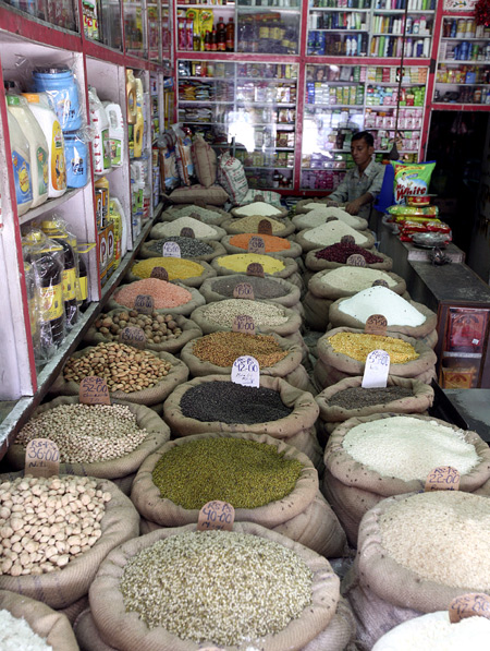 A retail trader arranges a bag containing pulses inside his shop in Jammu.