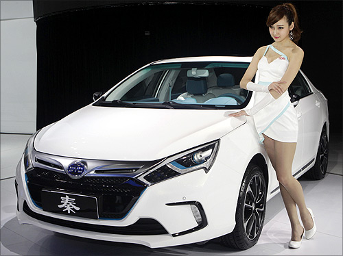 A model stands next to China's BYD QIN at Auto China 2012 in Beijing.
