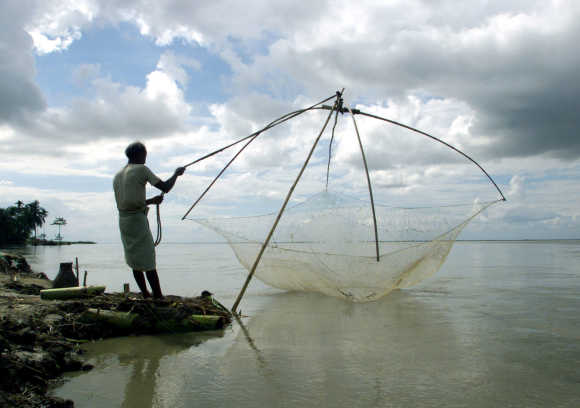 A fisherman arranges his net to fish on the waters of Bhramputra River in Simna.