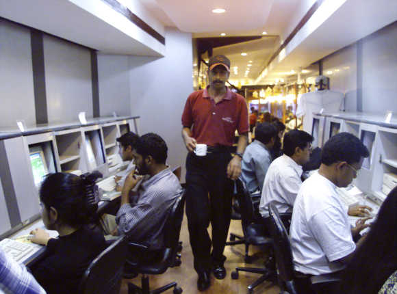 A waiter serves coffee to college students surfing the Internet at a cafe in Bangalore.
