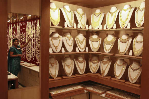 A salesgirl is reflected in a mirror inside a gold jewellery showroom in Kochi.