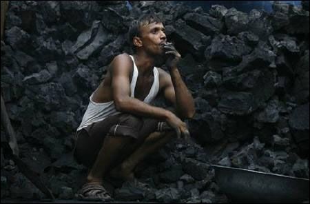 A labourer smokes a bidi, as he takes rest between unloading coal from a supply truck in Noida.