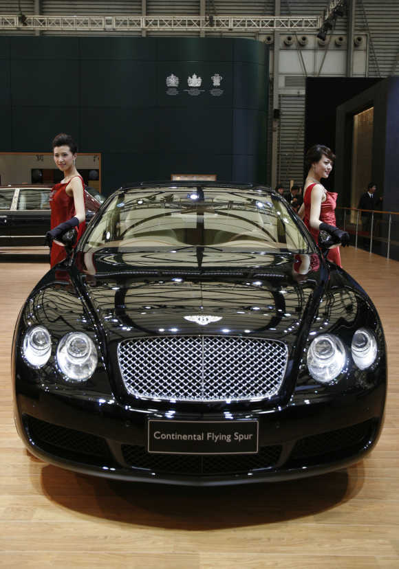 Models pose beside a Bentley Continental Flying Spur in Shanghai, China.