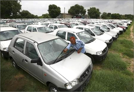 A worker adjusts the windscreen wipers of a parked Alto car at a Maruti Suzuki stockyard on the outskirts of Ahmedabad.