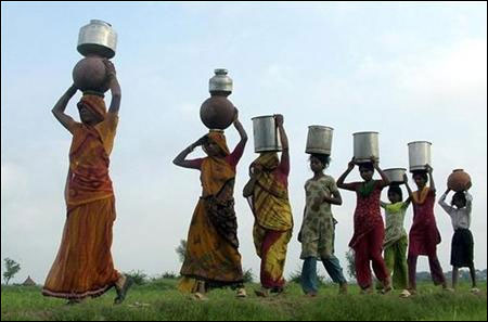 People carry pots containing water on their heads on the outskirts of Mathura.