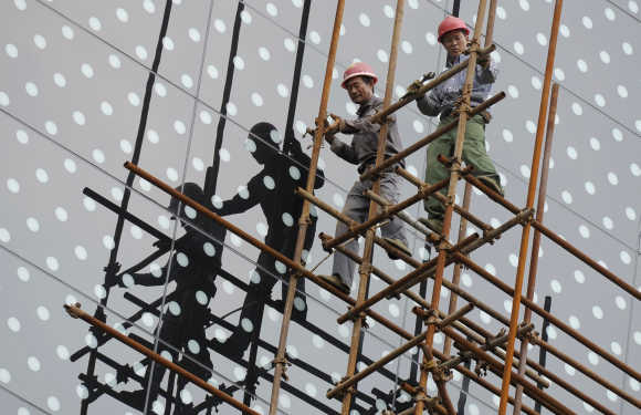 Labourers cast their shadows on the glass facade of a hotel as they take down scaffolding at a construction site in Nanjing, China.