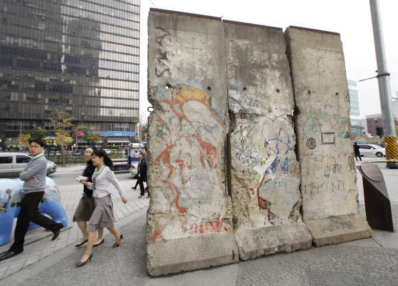 People walk past a section of the Berlin Wall displayed at Berlin Plaza in central Seoul.
