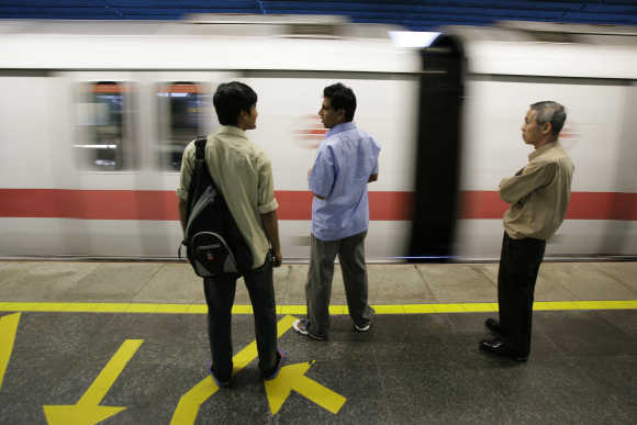 Commuters wait to board an MRT train at a station in Singapore.
