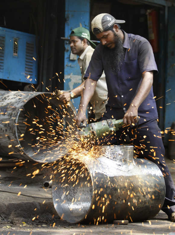 A worker uses an angle grinder at a small steel workshop in Mumbai.