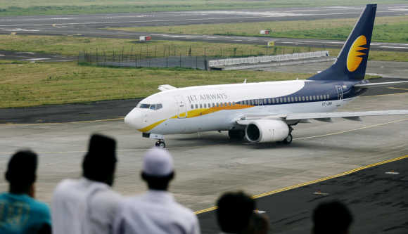 People look at a Jet Airways aircraft preparing to take-off in Mumbai.