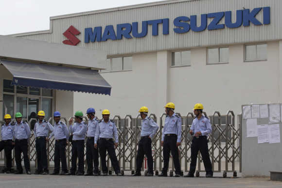 Private security guards stand outside the main entrance to the Maruti Suzuki plant where workers are striking in Manesar, Haryana.