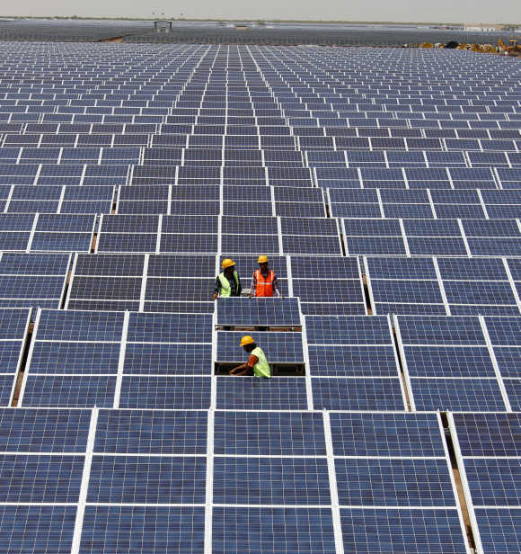 Workers install photovoltaic solar panels at the Gujarat solar park in Charanka.