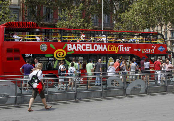 Tourists line up to board the city tour bus at Plaza Catalunya in central Barcelona.