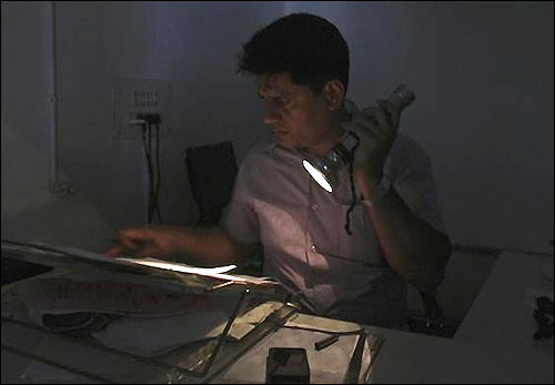 An officer reads documents with the help of a torch at the driving registration and license authority office during a power-cut in Chandigarh, July 31, 2012.