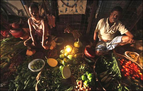 Vegetable vendors wait for customers at their stall during a power-cut in Kolkata.