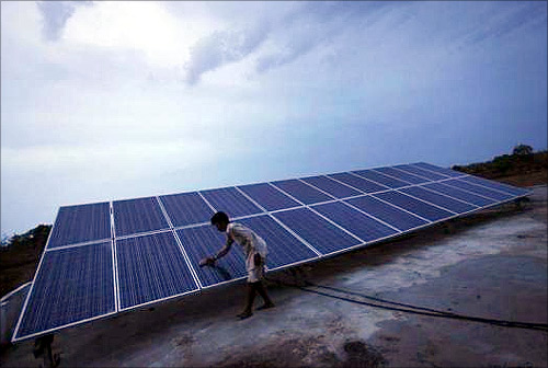 A man cleans panels installed at a solar plant at Meerwada village of Guna district in the central Indian state of Madhya Pradesh.