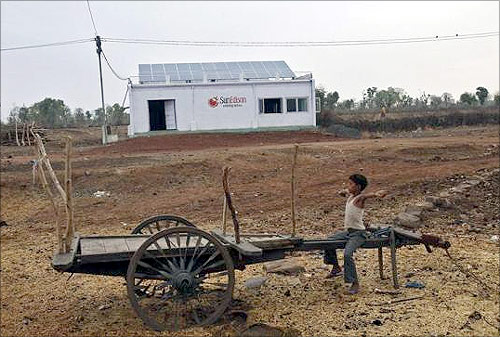 A boy sits on a cart in front of a solar power plant at Meerwada village of Guna district in Madhya Pradesh.