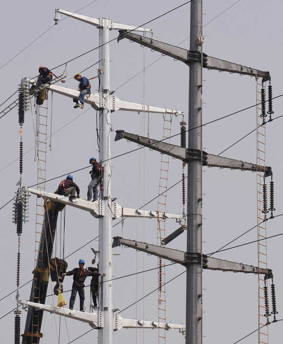 Labourers install electronic cables on power poles in Hefei, China.