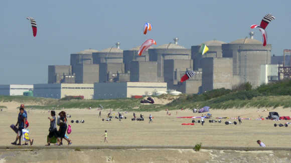 Kites fly in the sky as the Gravelines nuclear power plant is seen across the beach in Petit Fort Philippe, northern France.