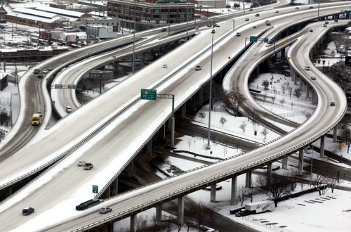 Cars travel on an almost deserted snow covered downtown highway after an overnight storm dropped five inches of snow in Dallas, Texas.