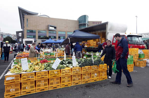 People buy fruits at a fruit and vegetable market in Wellington, New Zealand.