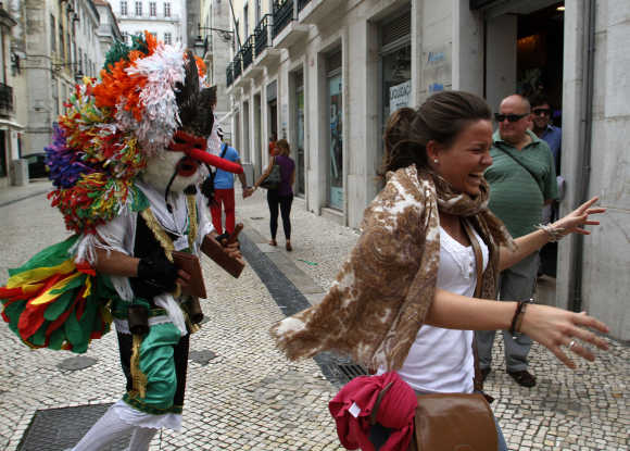 A reveler from the Portuguese village of Aveiro playfully chases a tourist during the Iberian Mask parade in Lisbon.