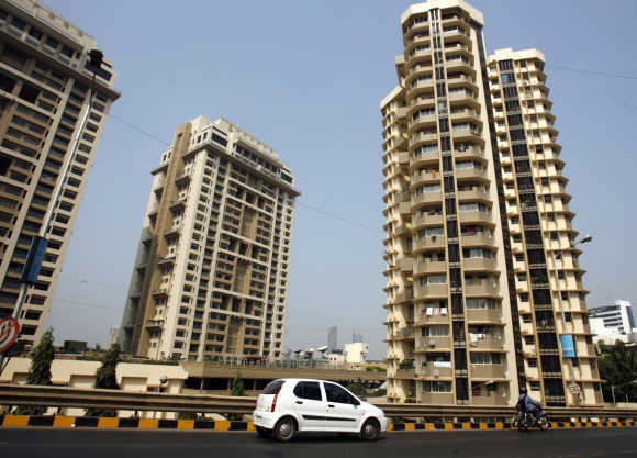 A vehicle drives past residential buildings in Mumbai.