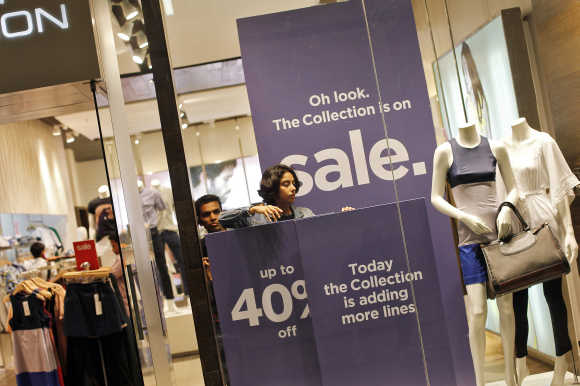 An employee adjusts the window display at a retail store inside a shopping mall in Mumbai.